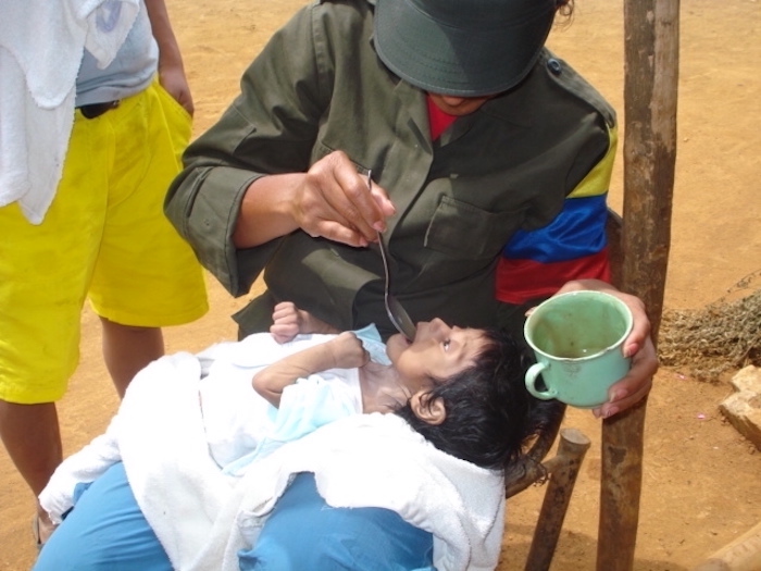 Guerrillera atiende a menor en Los Quingos, Cauca, Colombia.